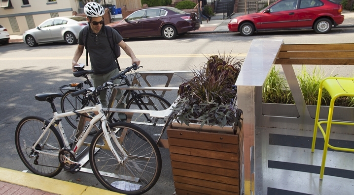 A bicyclist locking a bike to the built-in racks 