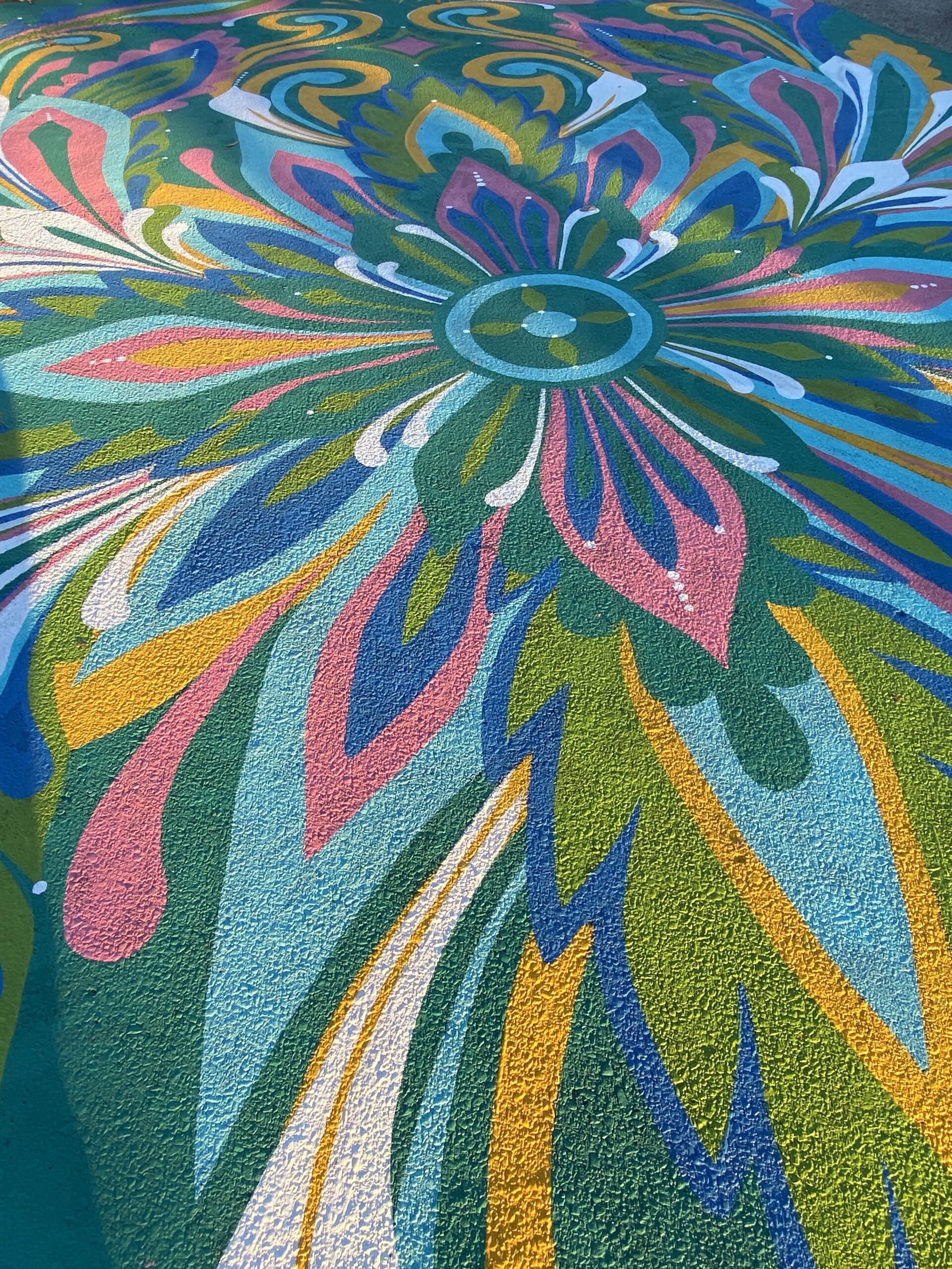 Close up shot of "Groove and Flow" ground mural at 49th & Baltimore. Mural is floral and abstract, featuring bright yellows, pinks, and jewel tones.