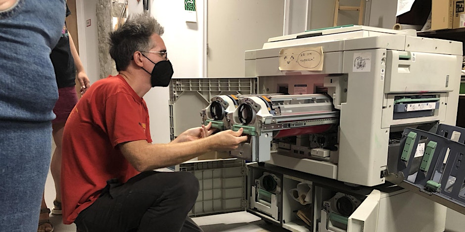 Person in red shirt operating a risograph machine