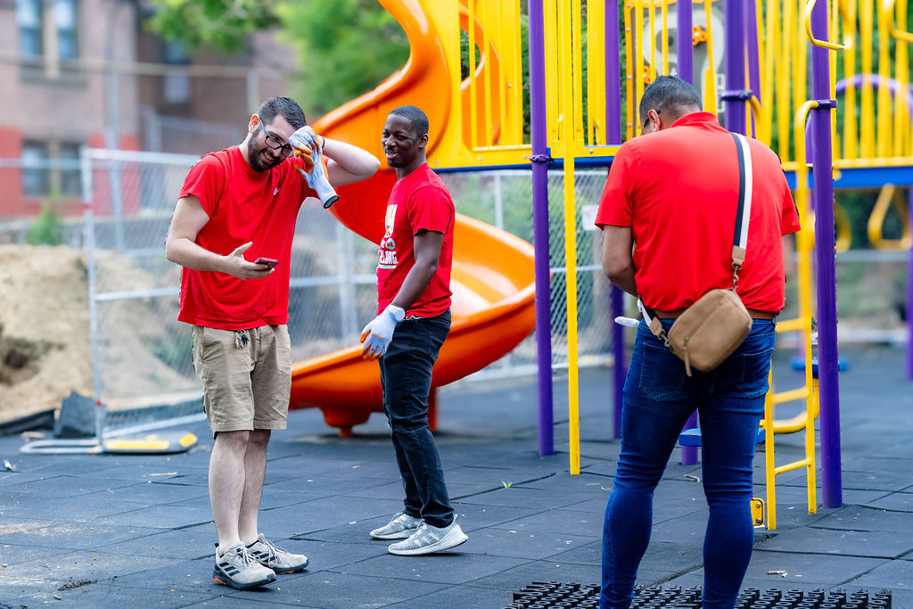 Volunteers smile and talk as they work to fix the playground floor