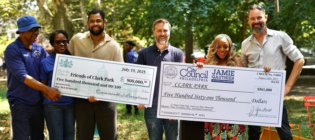 Elected Officials and UCD staff smiling, holding large checks
