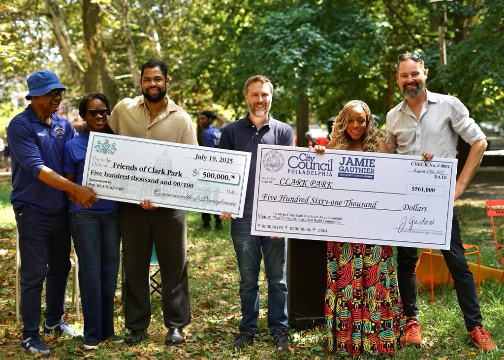 Elected Officials and UCD staff smiling, holding large checks