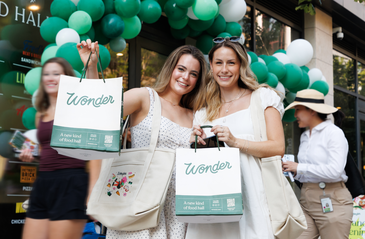 Two people smiling while standing outside of a new business during a grand opening