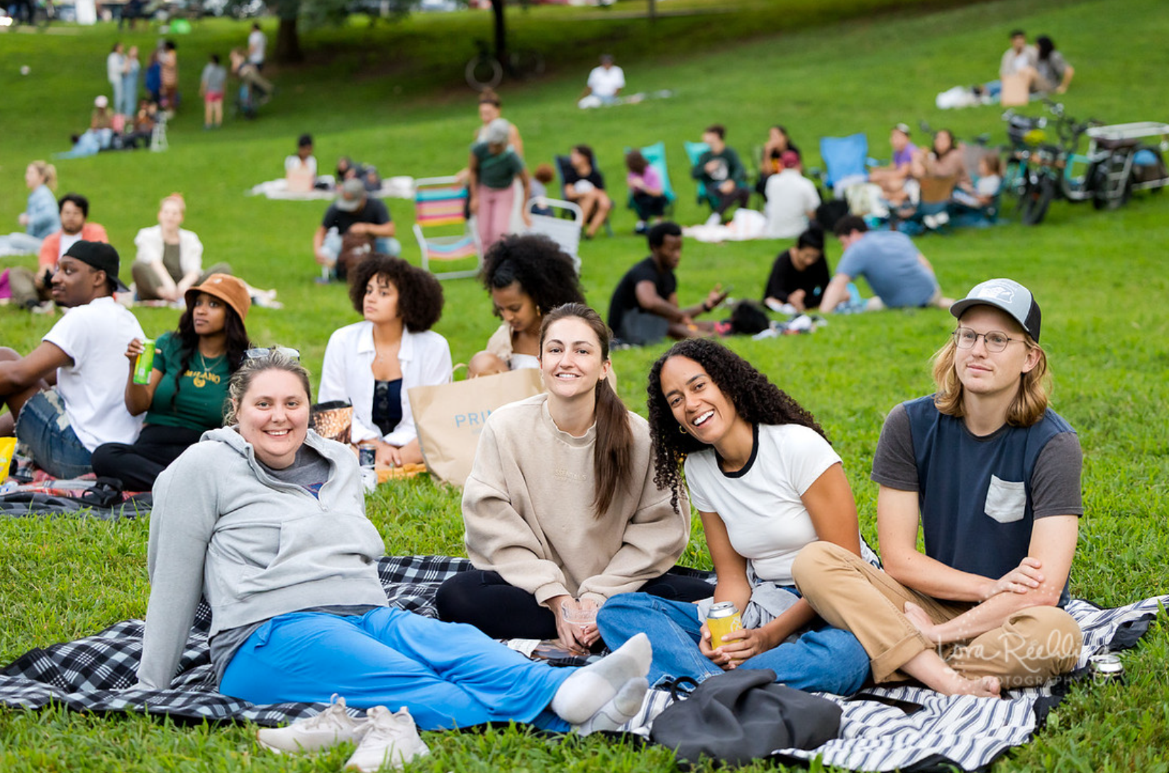 A group of people smiling sitting on blankets during Movies in Clark Park