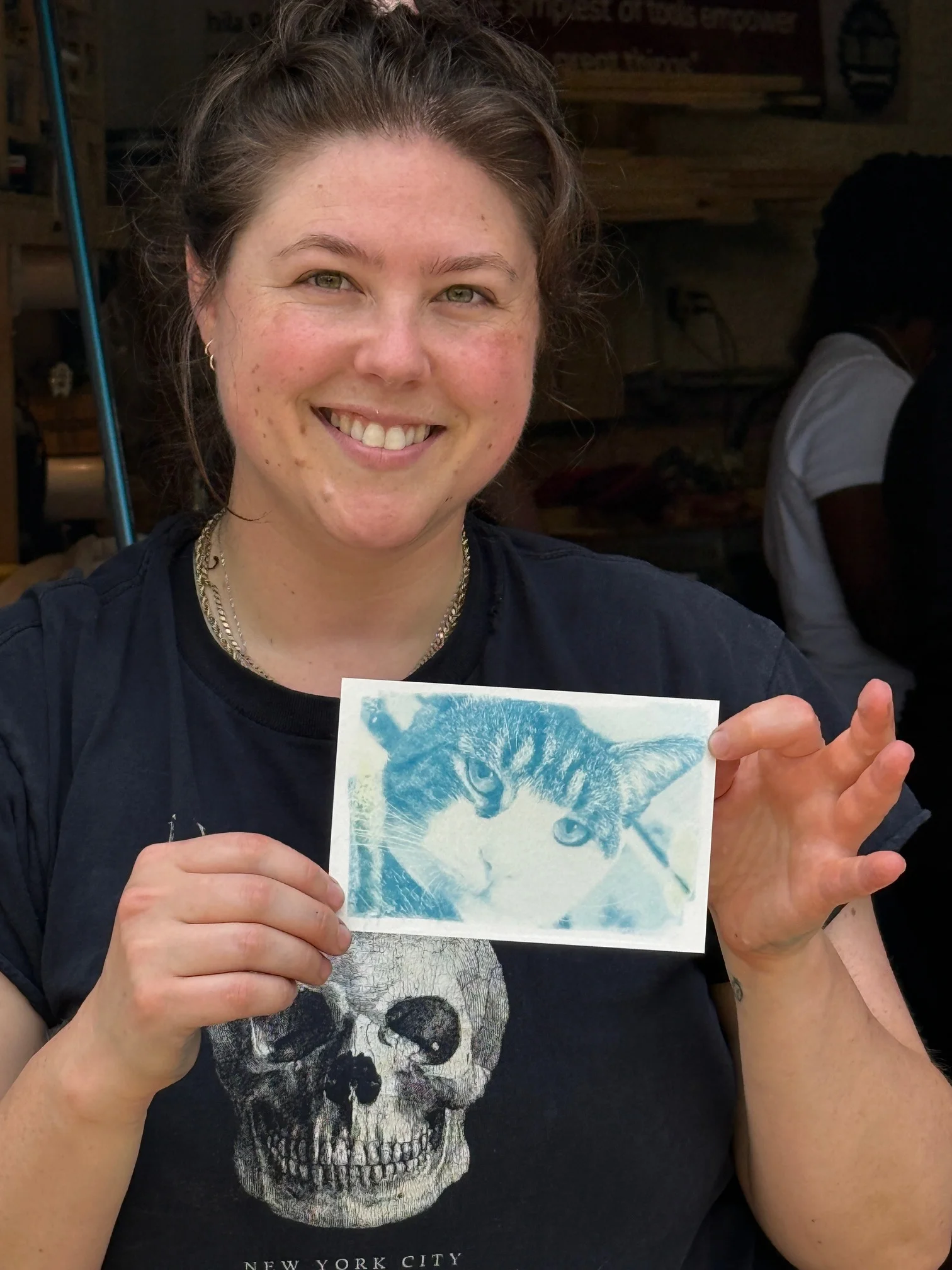 Person smiling, holding a cyanotype print of a cat