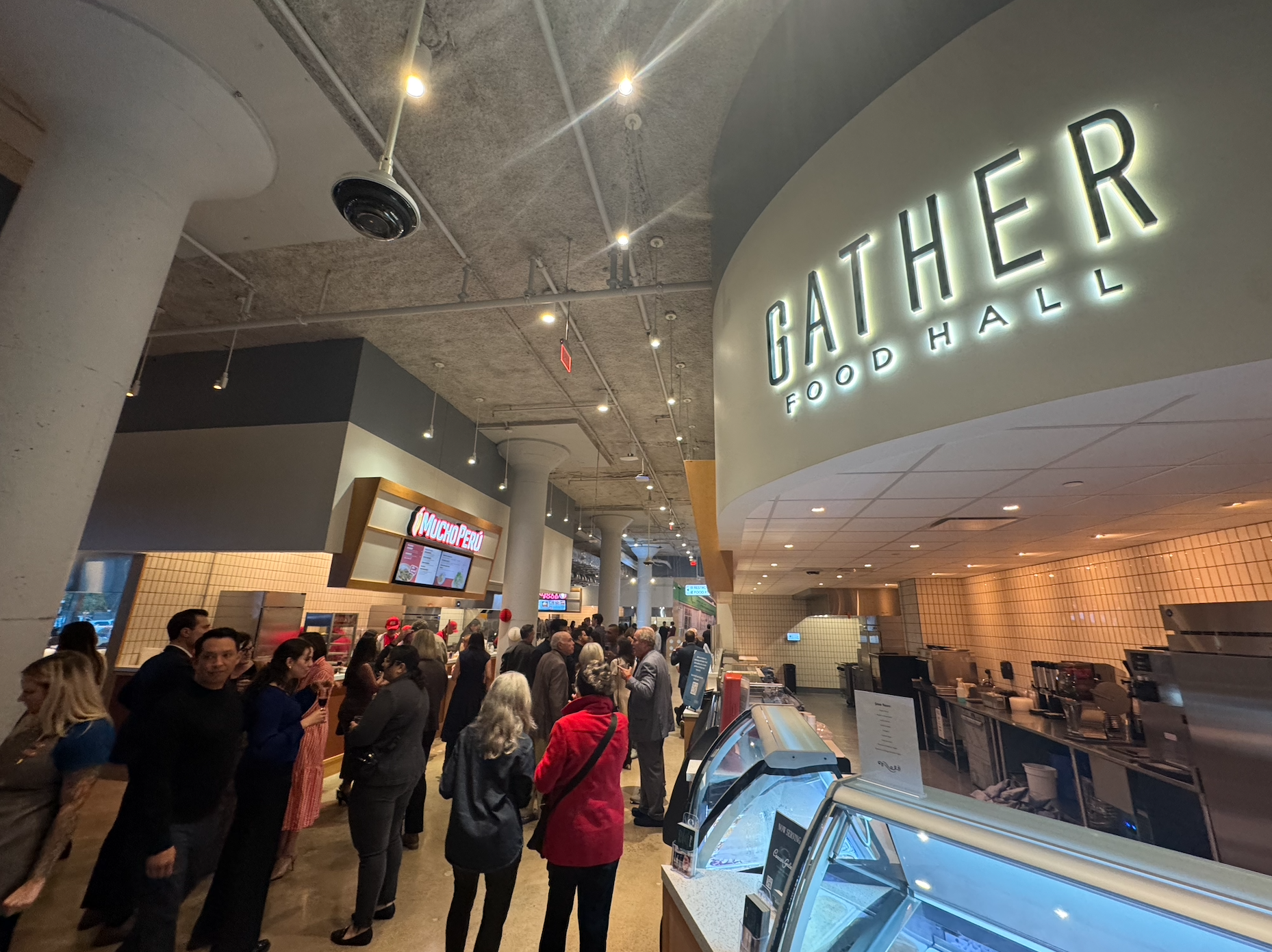 Image form the inside of Gather Food Hall, people stand, wait for food, and socialize with each other