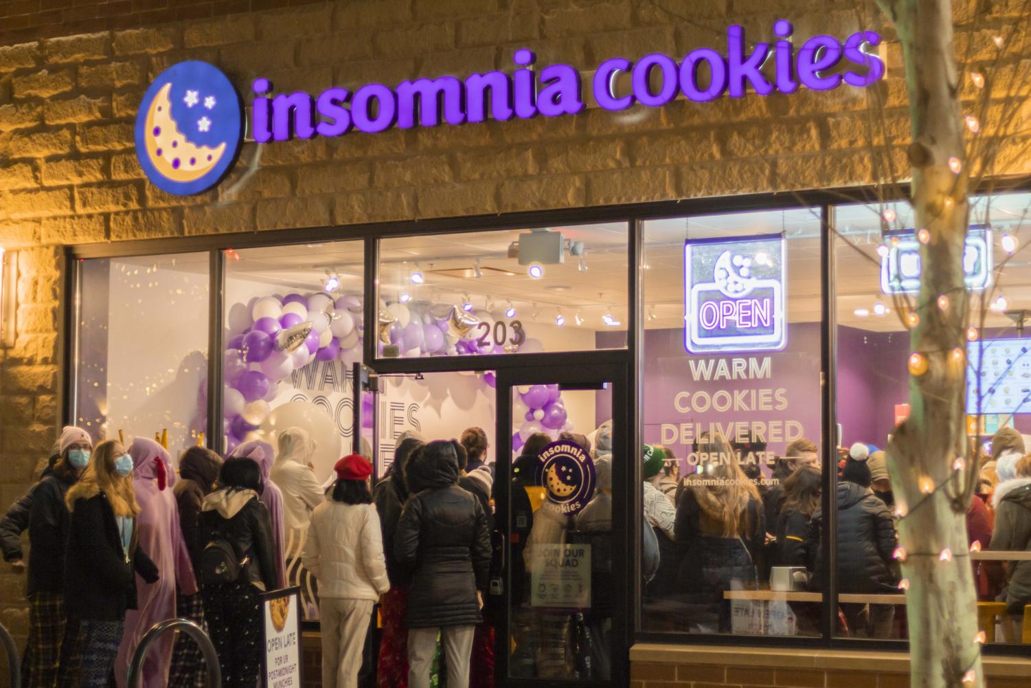Exterior of an insomnia cookie, with a line spilling out of the store and onto the sidewalk