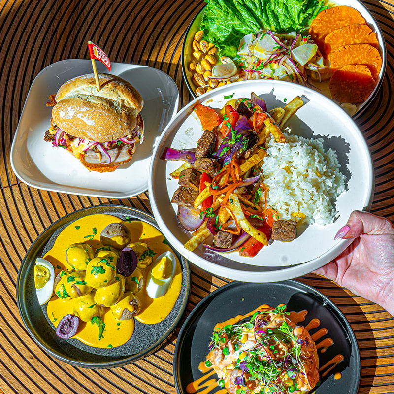 A plate of food from Mucho Peru, featuring sandwiches, saucy platters and more.
