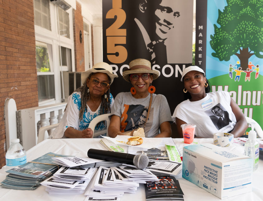 A group of volunteers smile while sitting outside of the Paul Robeson House outside of their West Philadelphia location.
