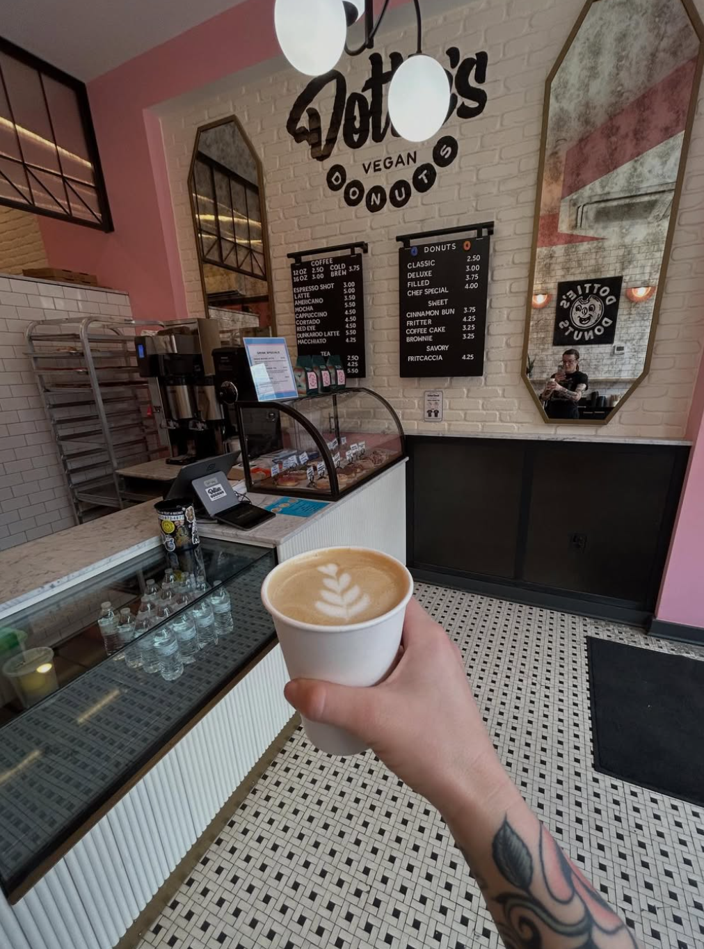 Image of person holding a latte in the interior of Dottie's Donuts