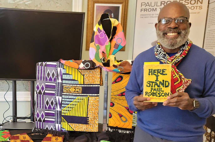 A visitor of the Paul Robeson House in West Philadelphia smiles while holding a book.