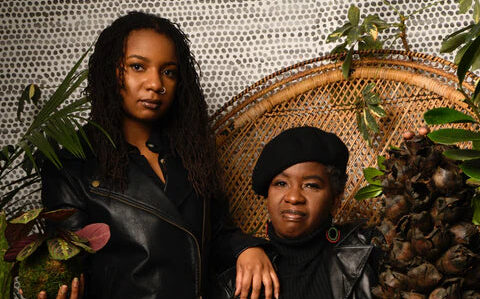 The owners of Philadelphias Plant & People pose surrounded by plants, seated in a wicker chair