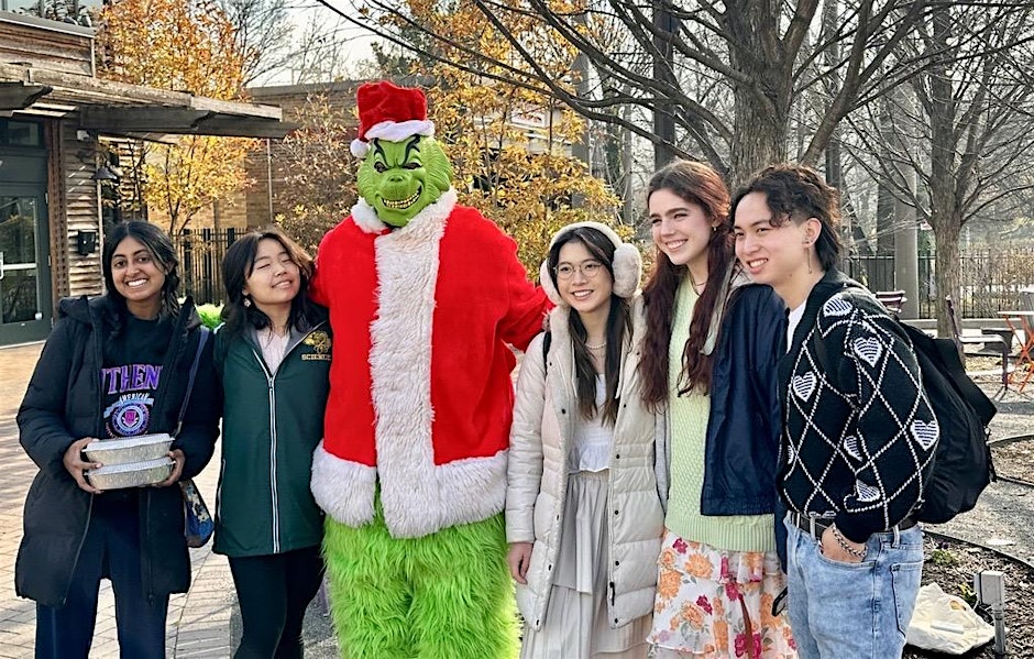 A group of people stand and pose with the Grinch