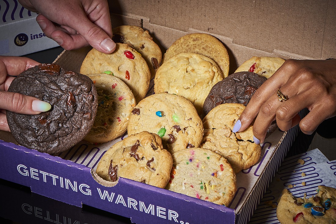 People grabbing cookies from an insomnia cookies box