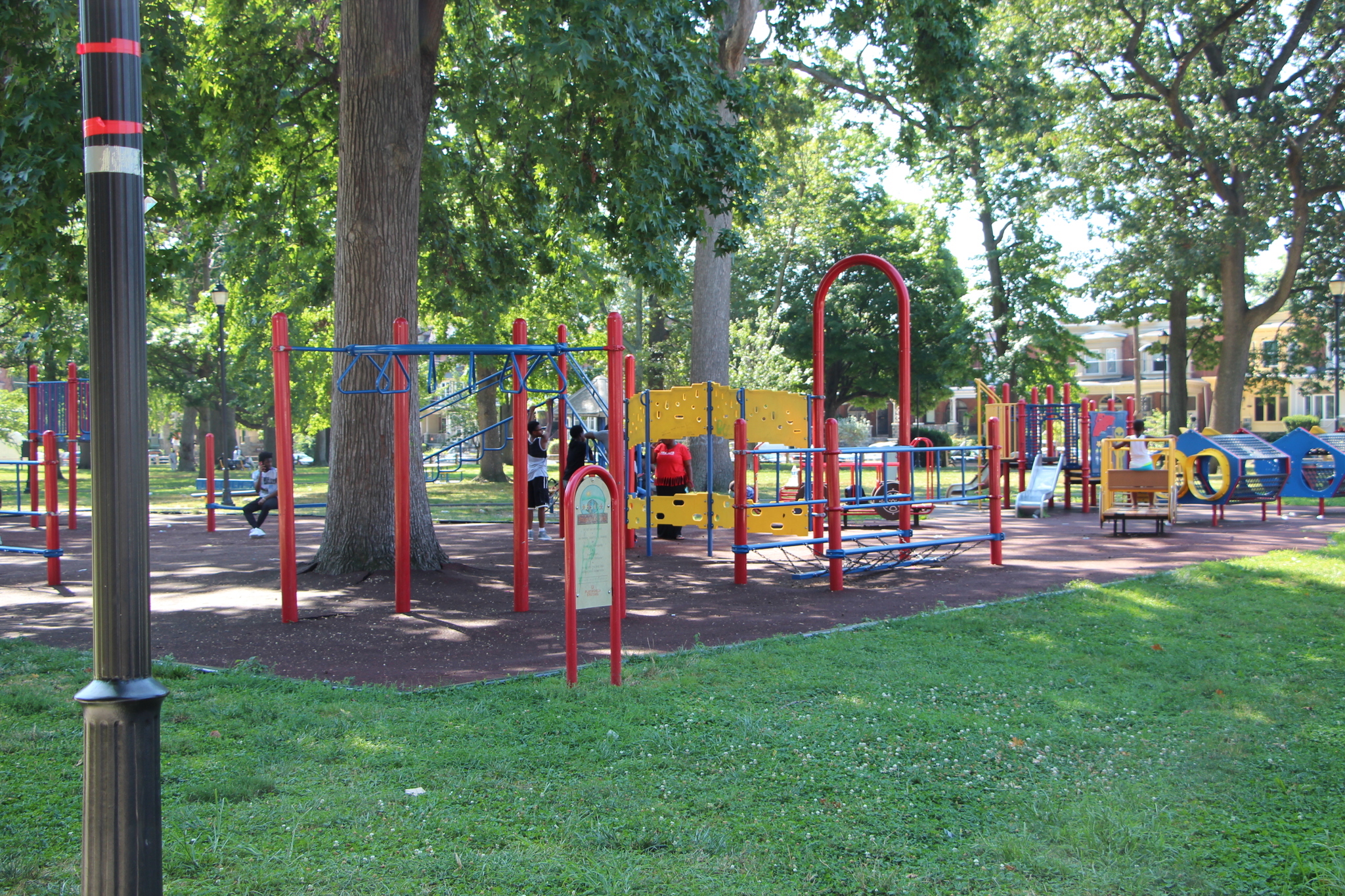 Malcolm X Park on a sunny day. The park has a playground surrounded by trees