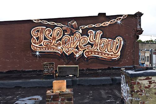 An image of a public art mural by Steve Powers. the mural is a graphic image of a gold chain, reading "I Love You"