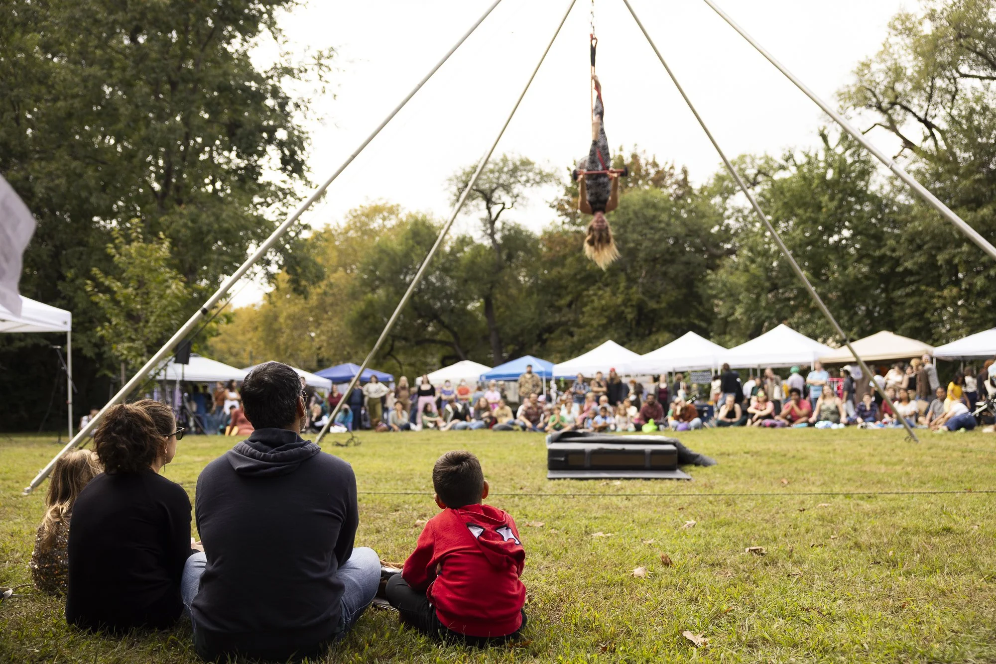 Image of the springtime west craft fest. A group of people watch a trapeze artist perform