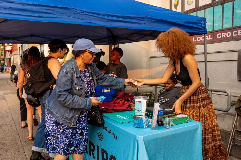 A vendor sells something to a community member at the Baltimore Ave Dollar Stroll