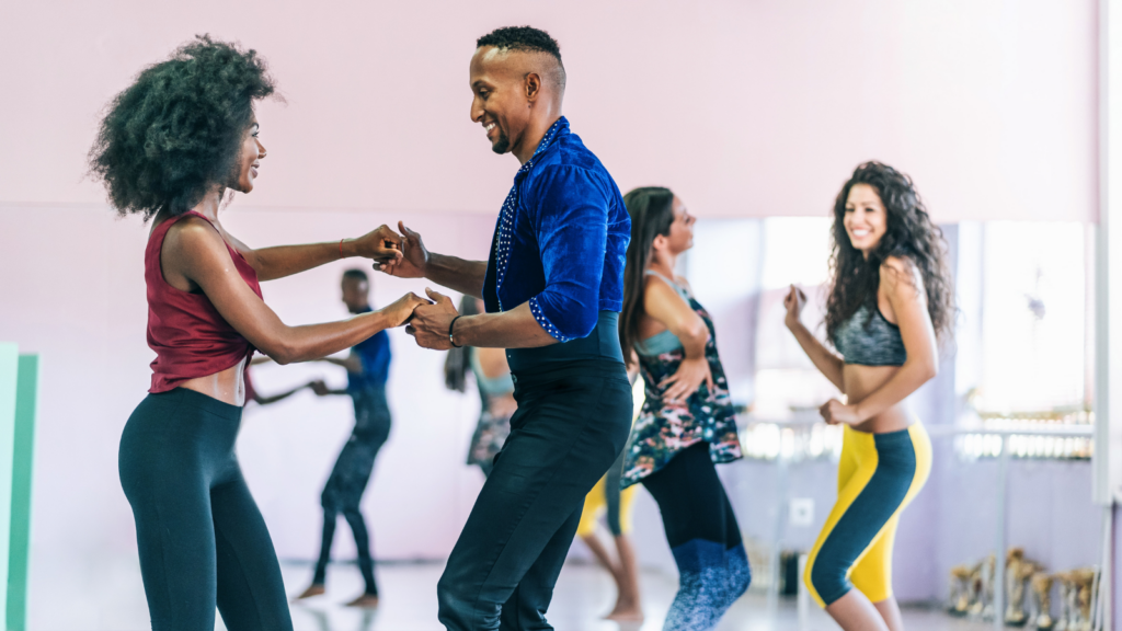 A group of people smile while participating in a multicultural dance class