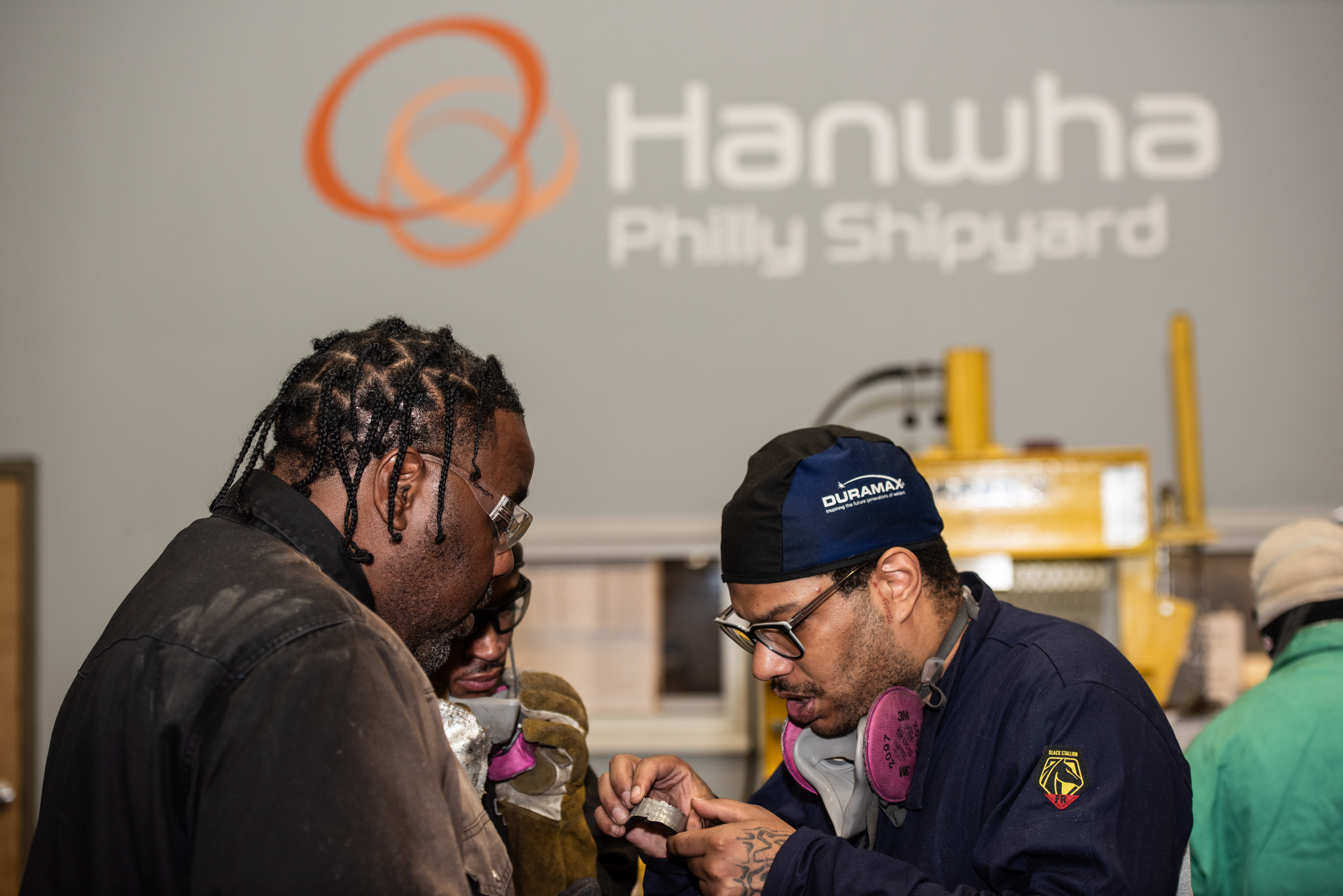 Participants in the Hanwha Welder Program examine their welding results